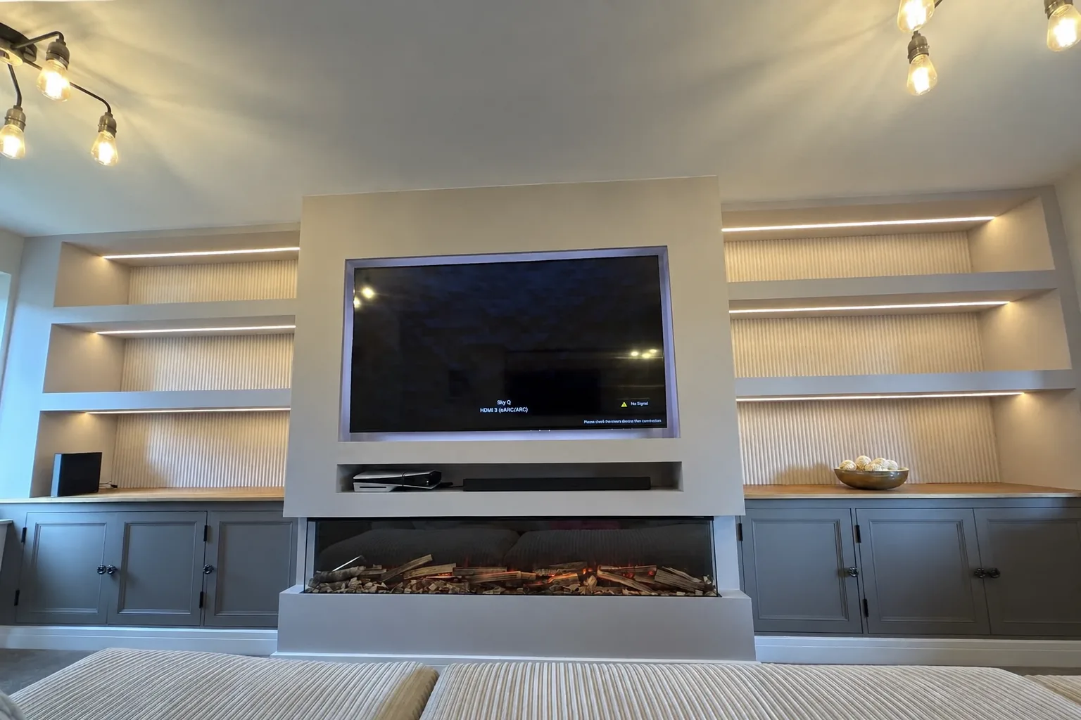 Finished media wall with inset fire, recessed TV and LED-lit shelves